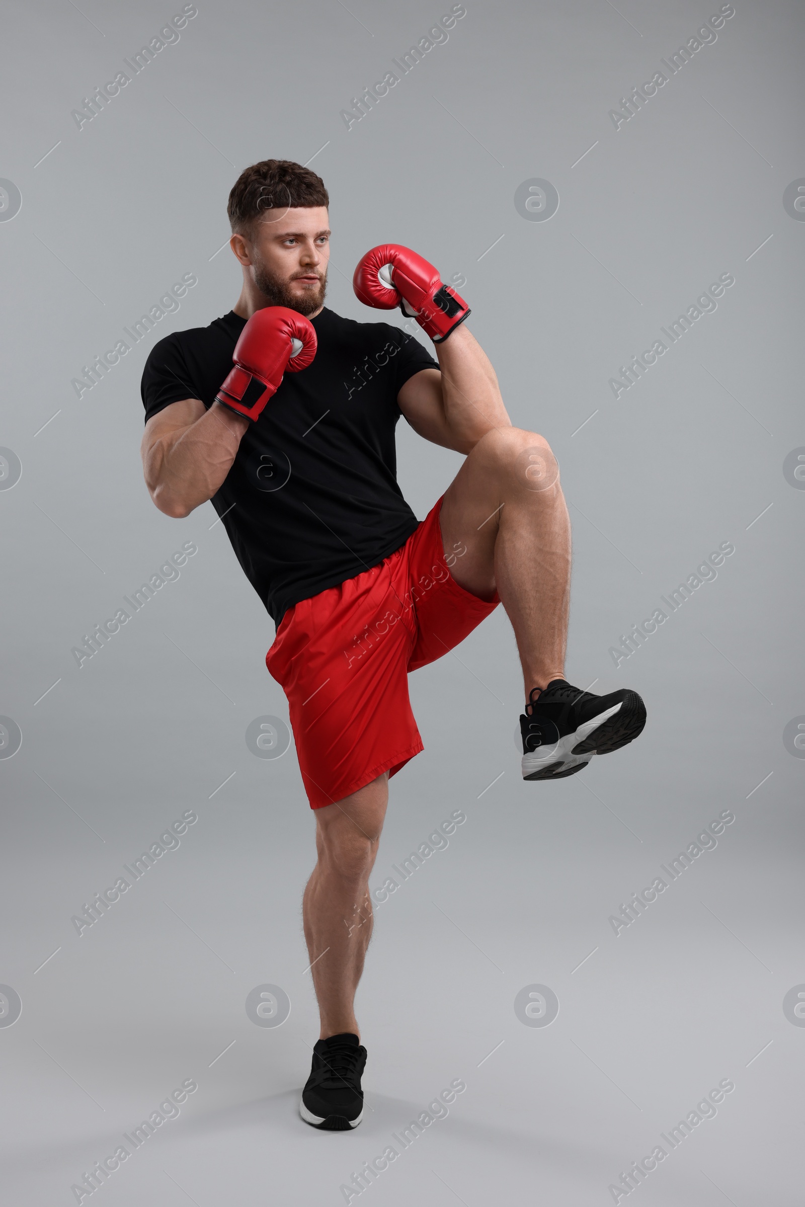 Photo of Man in boxing gloves fighting on grey background