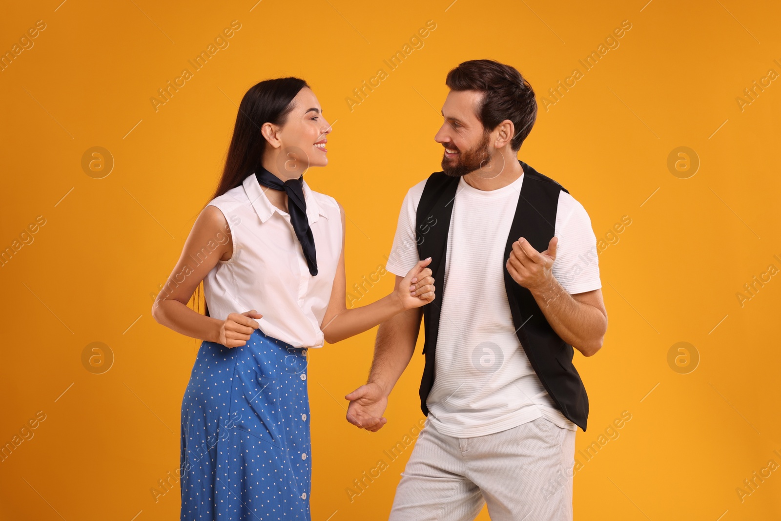 Photo of Happy couple dancing together on orange background