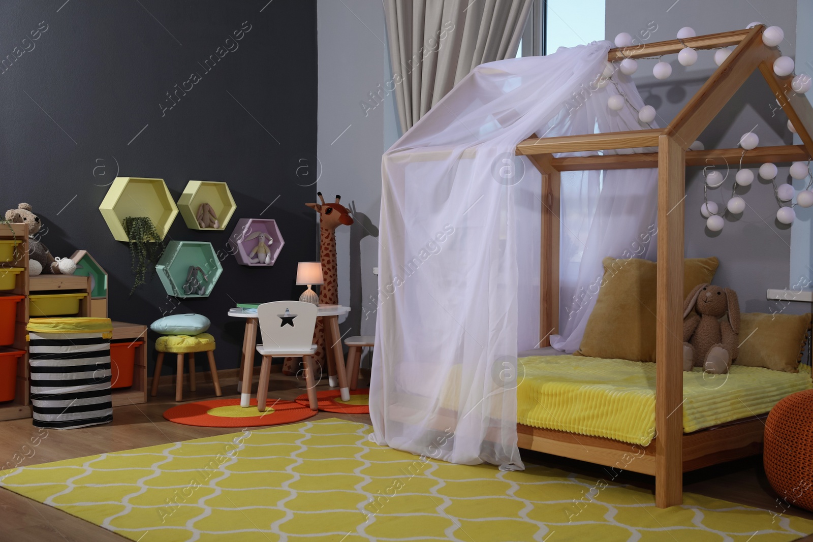 Photo of Stylish child room interior with comfortable house bed and toys