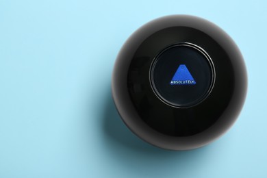 Photo of Magic eight ball with prediction Absolutely on light blue background, top view. Space for text