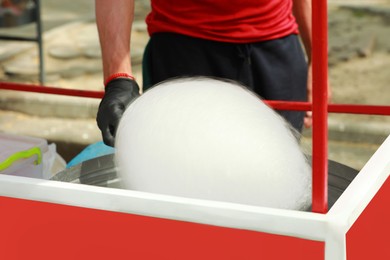 Photo of Man making cotton candy with machine outdoors, closeup