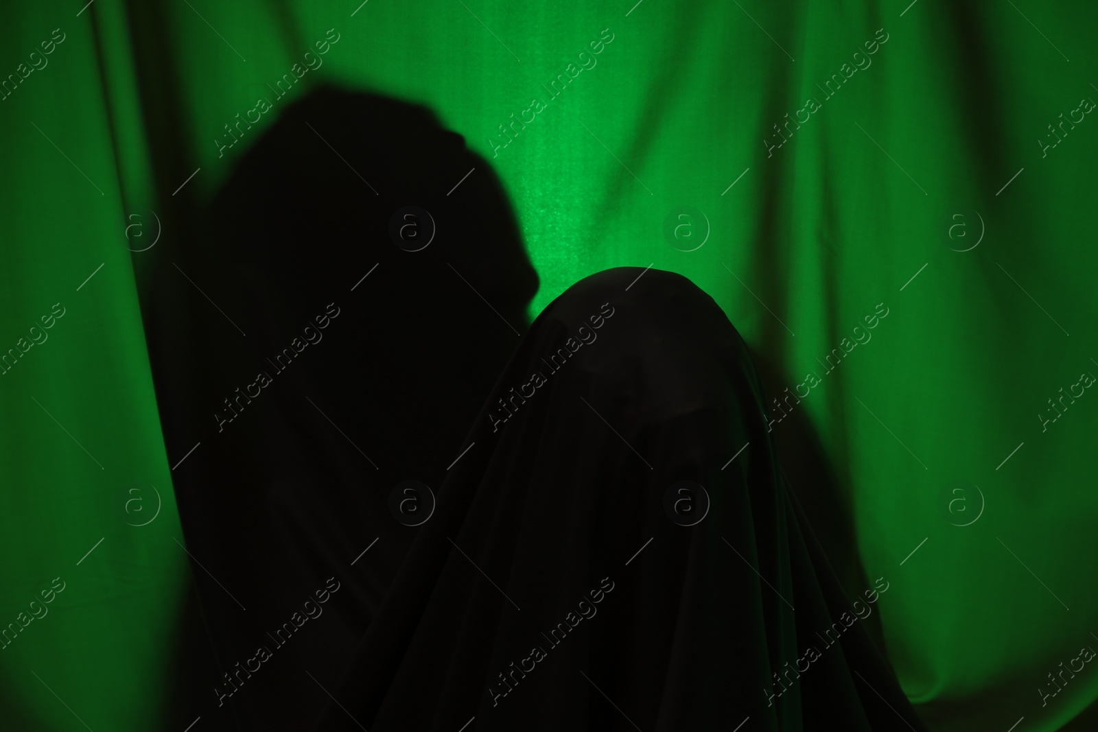 Photo of Silhouette of creepy ghost behind dark green cloth