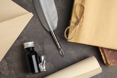 Flat lay composition with feather pen and bottle of ink on grey table