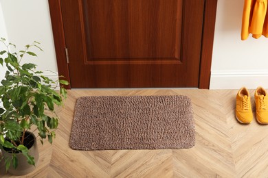 Clean door mat on wooden floor in hall, above view