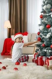 Photo of Cute little girl decorating Christmas tree at home