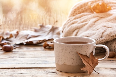 Composition with cup of hot cozy drink and autumn leaves on windowsill. Space for text