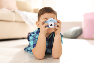 Photo of Little photographer taking picture with toy camera at home