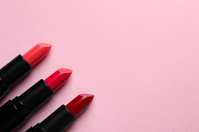 Photo of Many bright lipsticks on pink background, flat lay. Space for text