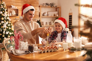 Photo of Happy father and his son making dough for Christmas cookies at home