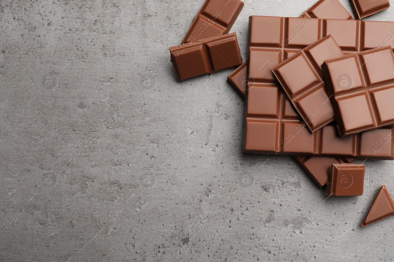 Photo of Delicious milk chocolate on light grey table, flat lay. Space for text