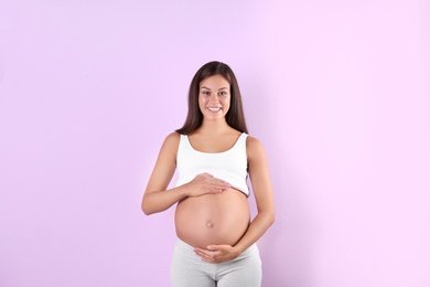 Photo of Happy pregnant woman posing on color background