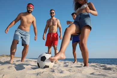 Group of friends playing football on beach