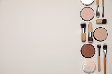 Different face powders and makeup brushes on beige background, flat lay. Space for text