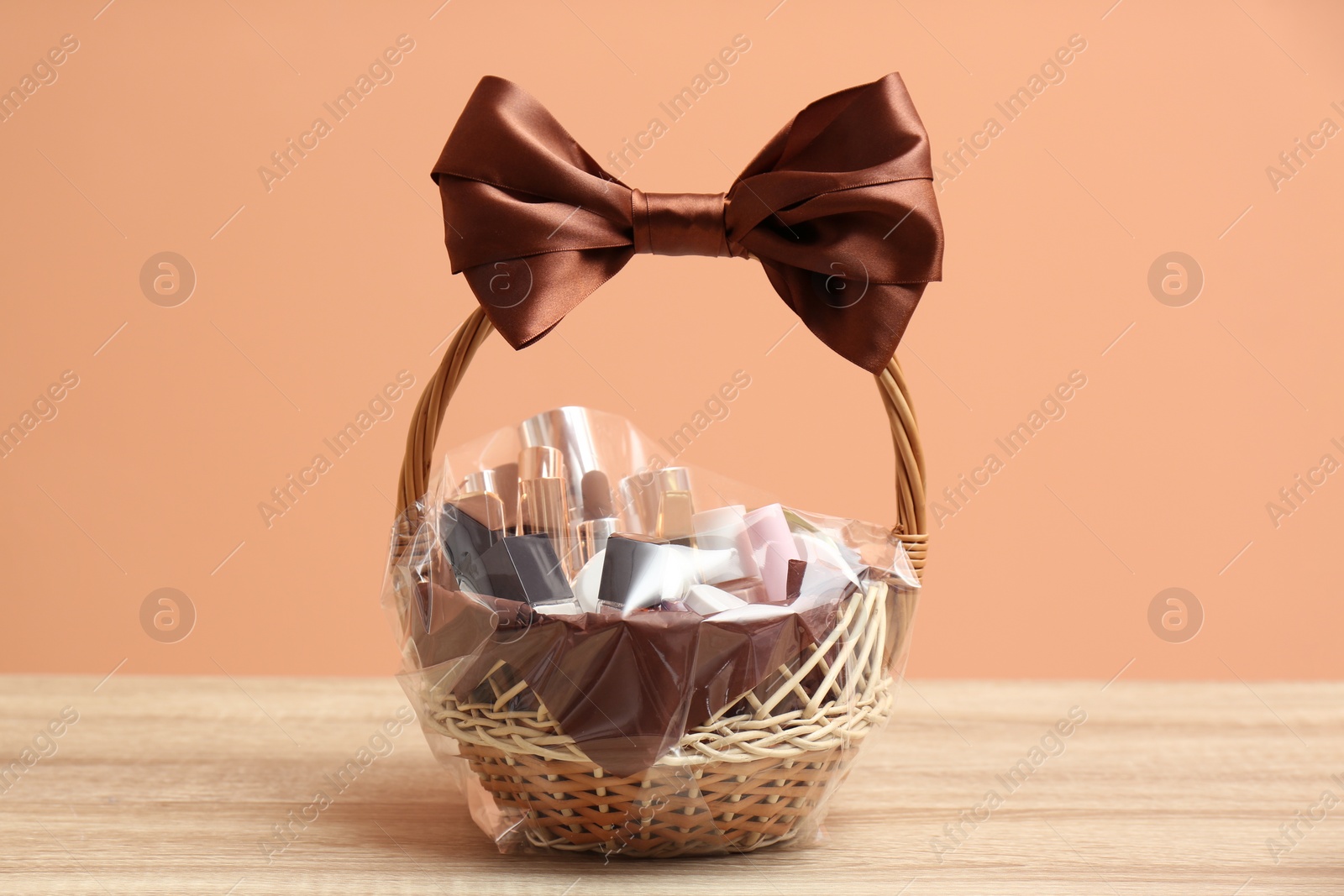 Photo of Wicker gift basket with cosmetic products on wooden table