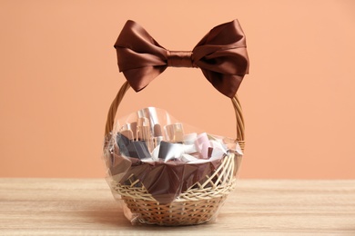 Wicker gift basket with cosmetic products on wooden table