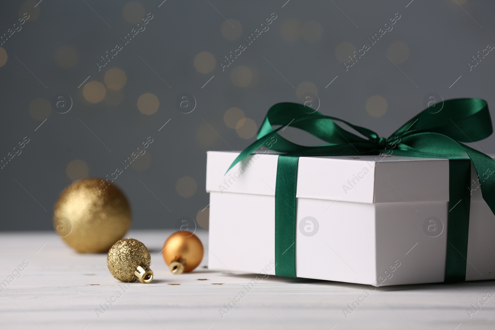 Photo of Gift box and Christmas decor on white wooden table. Space for text