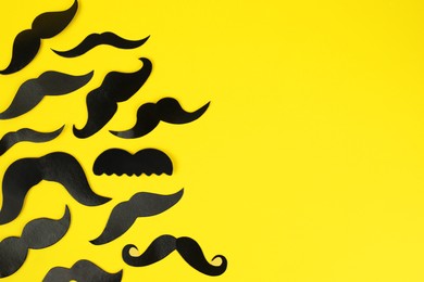Photo of Fake paper mustaches on yellow background, flat lay
