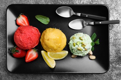 Photo of Strawberry, lemon and pistachio ice cream scoops served on grey table, top view
