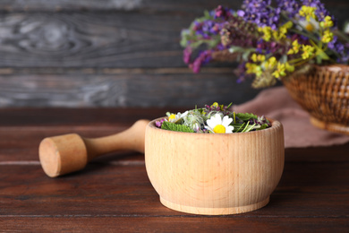 Photo of Mortar with healing herbs and pestle on wooden table