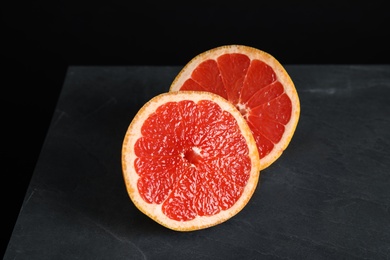 Photo of Halves of tasty ripe grapefruit on black background