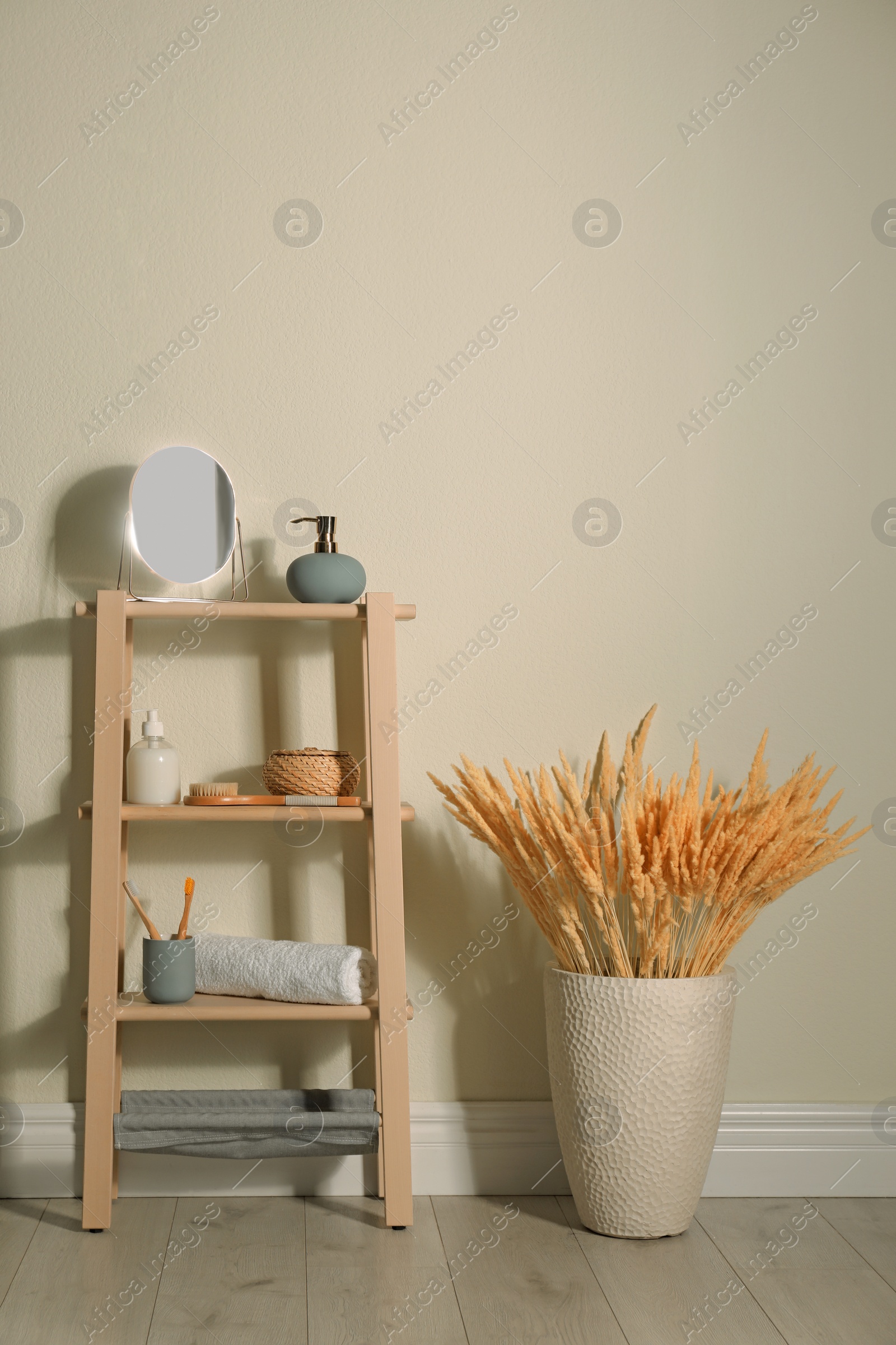 Photo of Wooden shelving unit with toiletries near light wall indoors. Bathroom interior element