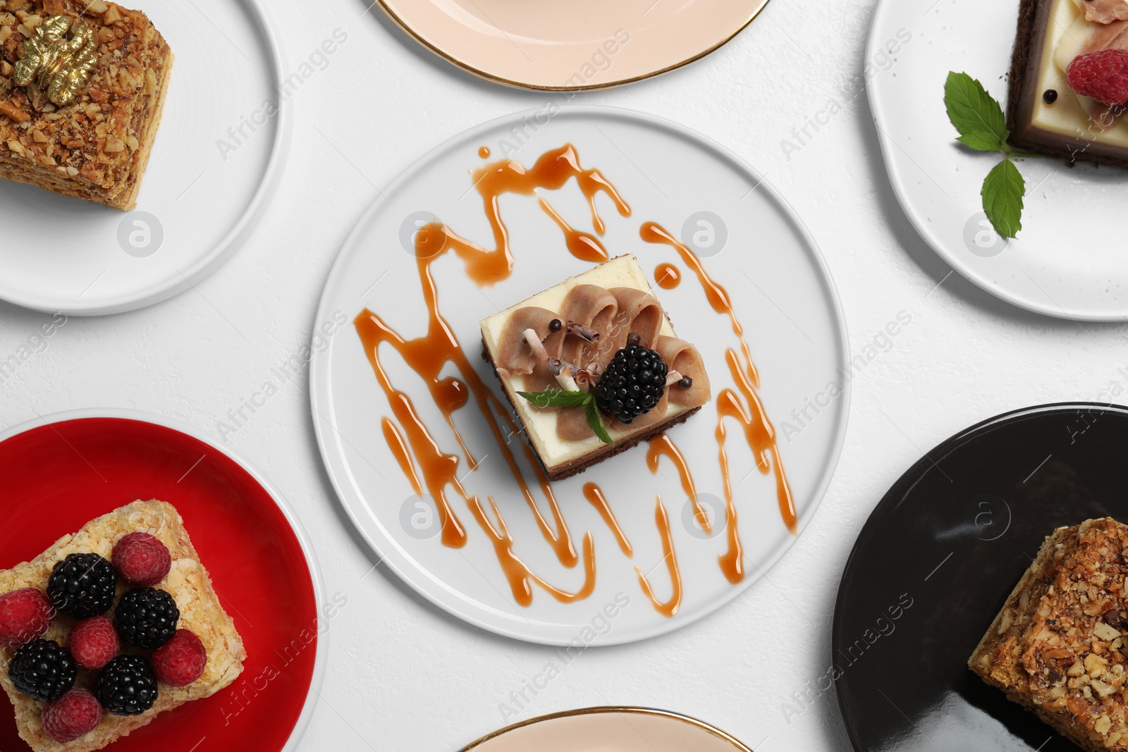 Photo of Pieces of different tasty cakes on white table, flat lay