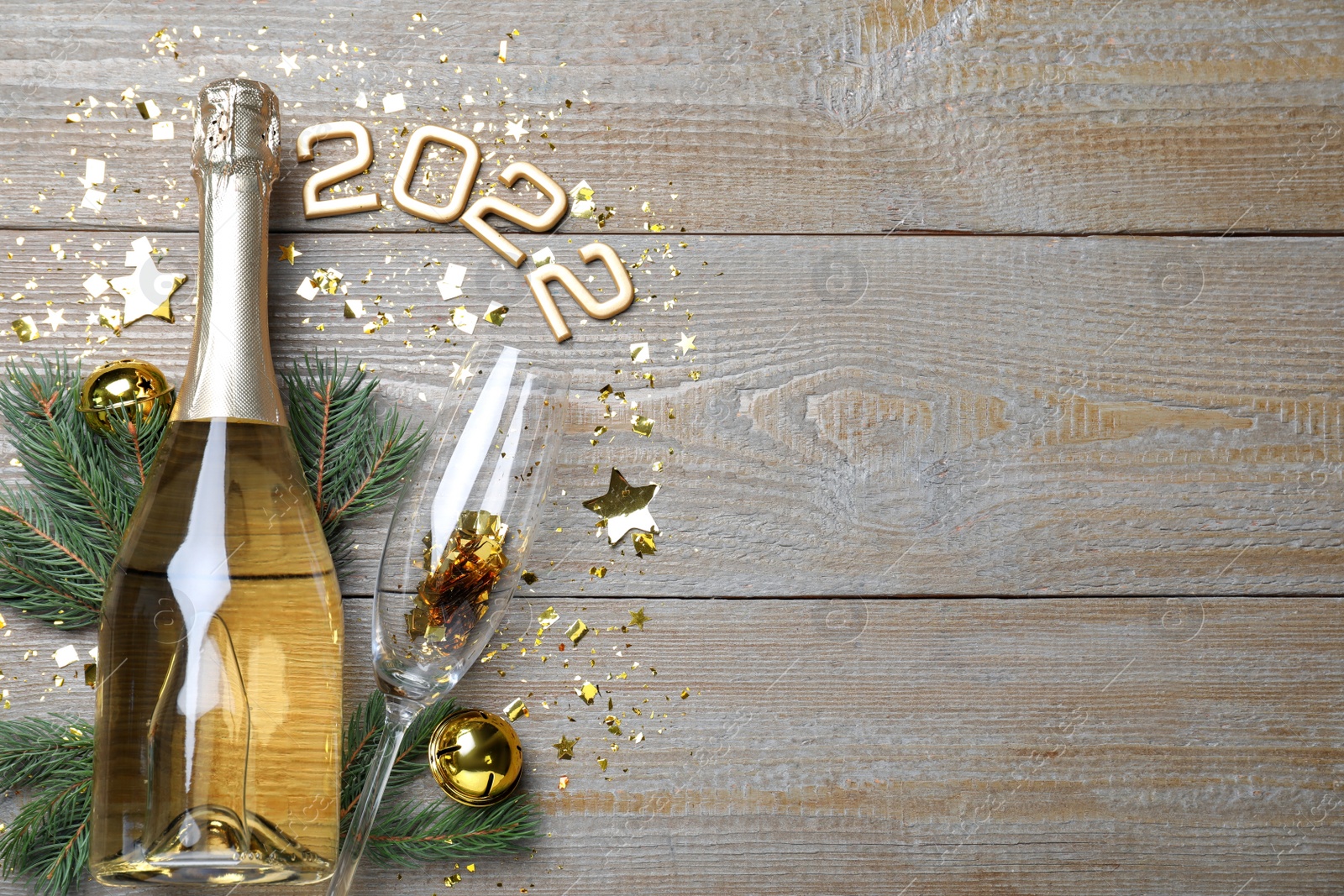 Photo of Happy New Year 2022! Flat lay composition with bottle of sparkling wine on wooden table, space for text