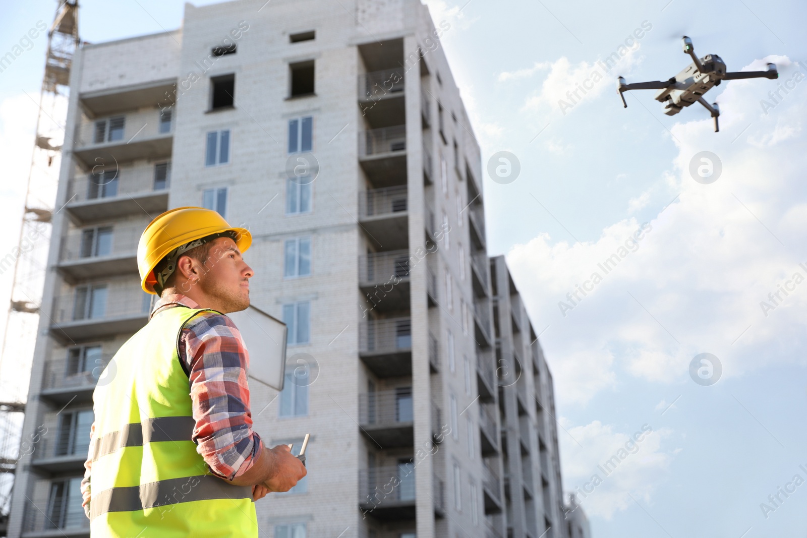 Photo of Builder operating drone with remote control at construction site. Aerial survey