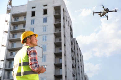 Builder operating drone with remote control at construction site. Aerial survey