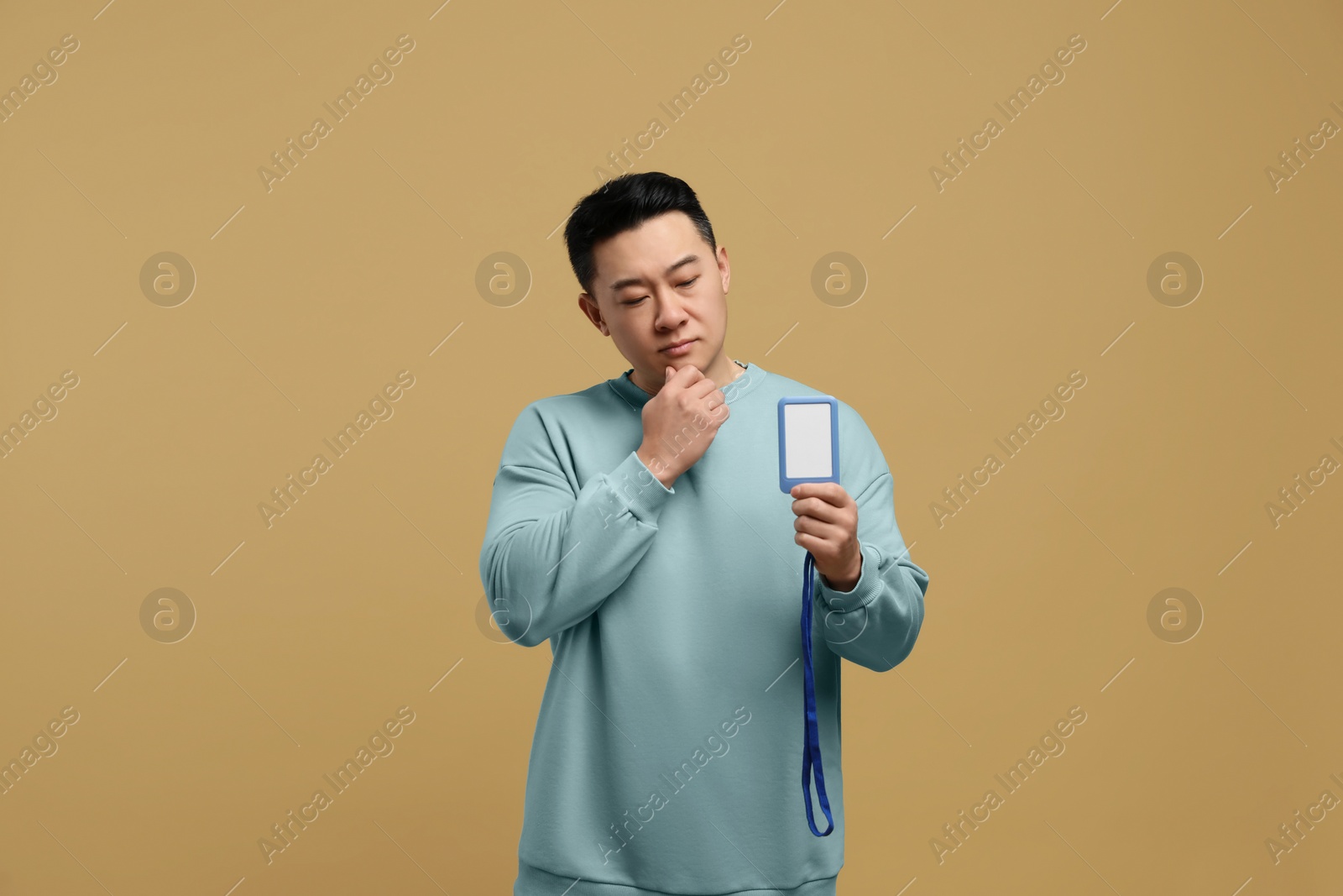 Photo of Emotional asian man with vip pass badge on beige background