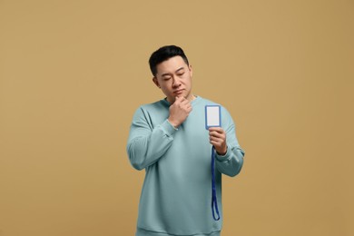 Photo of Emotional asian man with vip pass badge on beige background