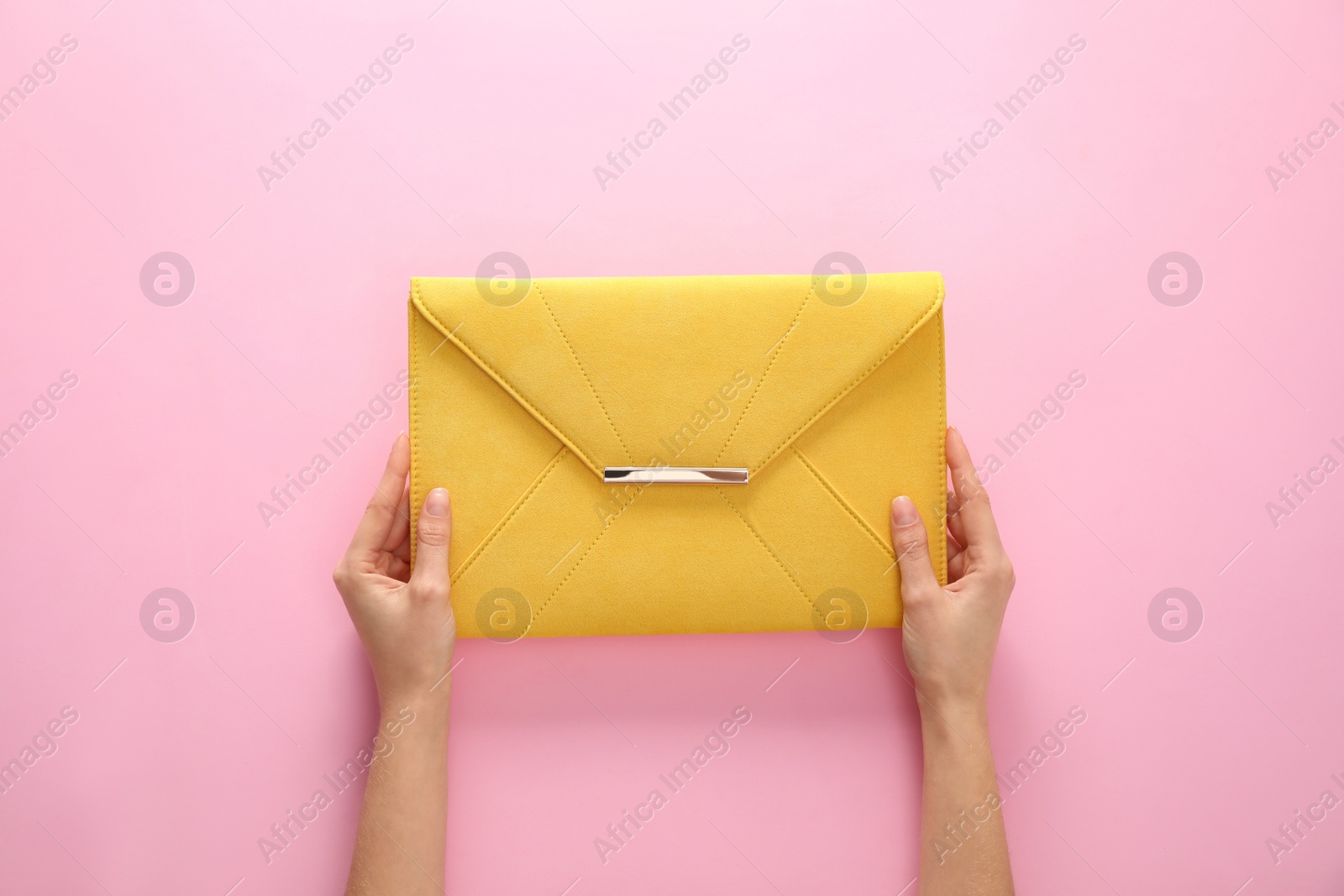 Photo of Woman holding stylish envelope bag on pink background, closeup