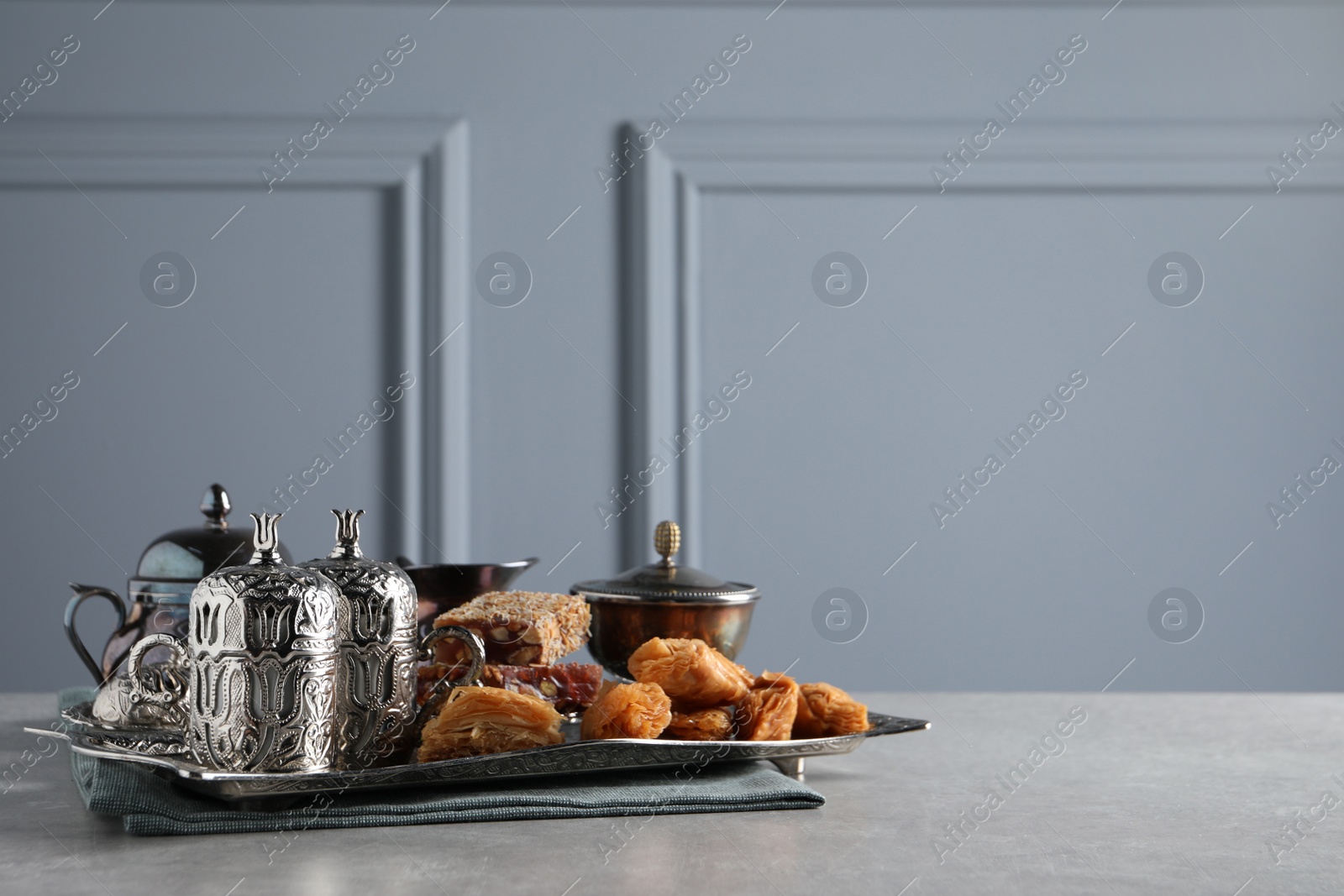 Photo of Tea, baklava dessert and Turkish delight served in vintage tea set on grey textured table, space for text