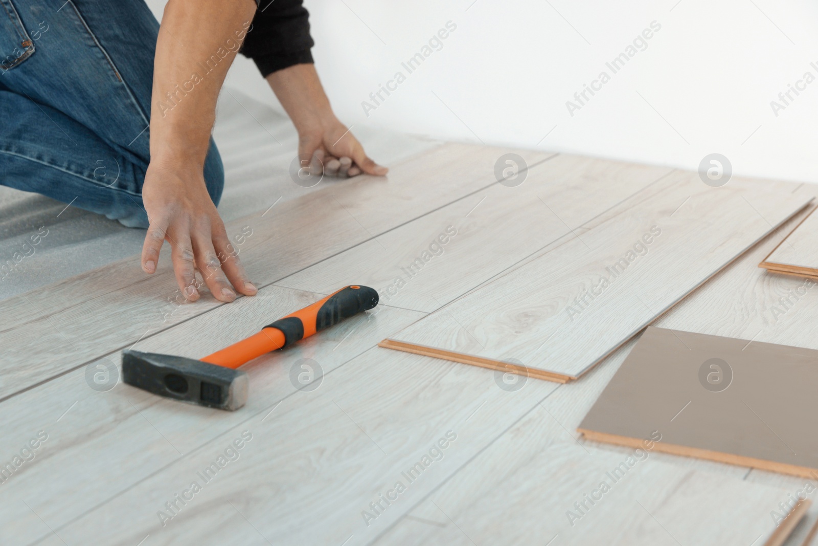 Photo of Worker installing new laminate flooring in room, closeup