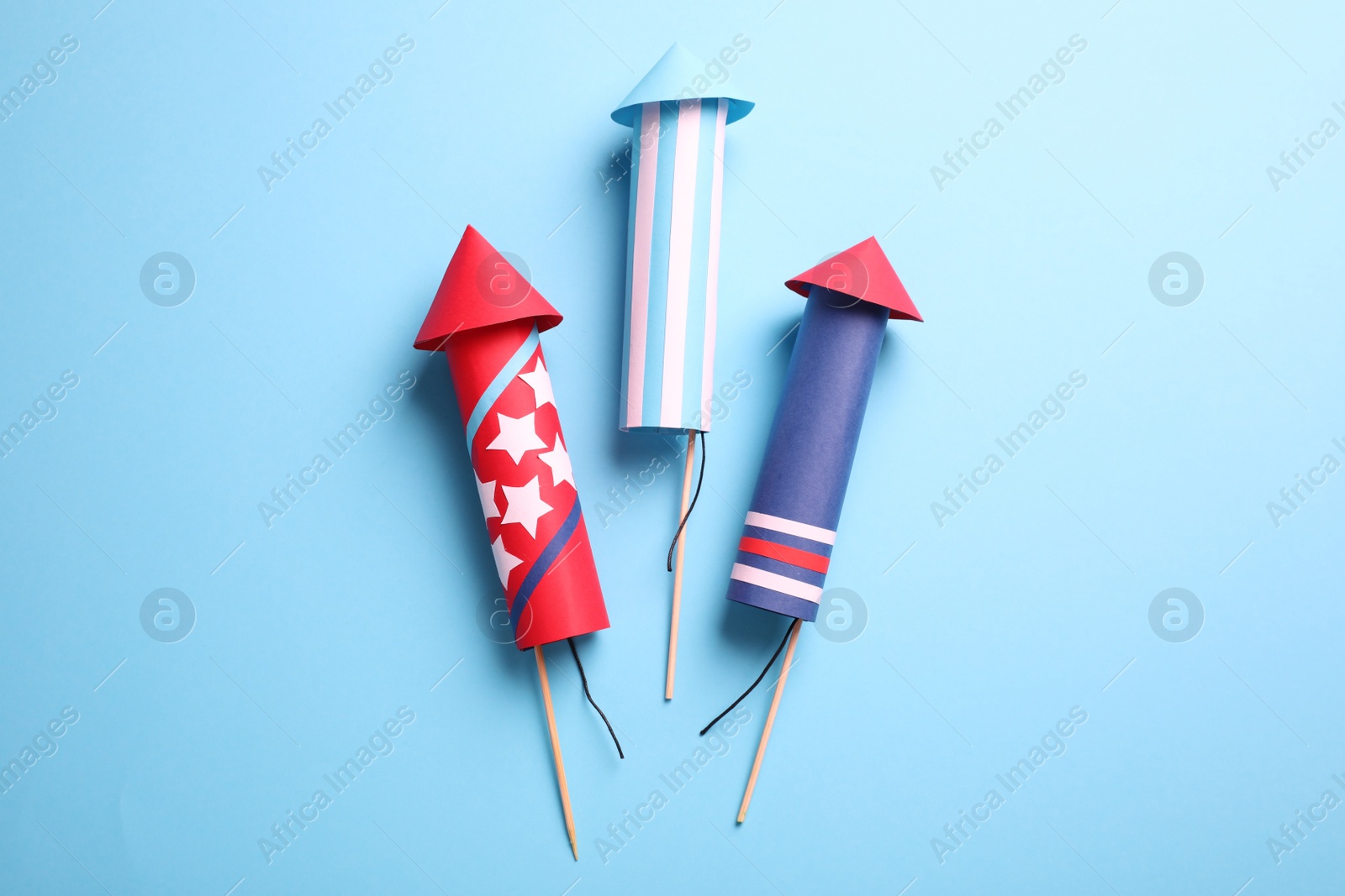 Photo of Firework rockets on light blue background, flat lay