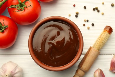 Flat lay composition with tasty barbeque sauce in bowl on white wooden table