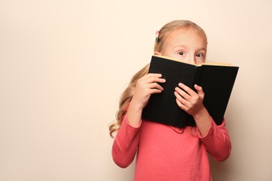 Photo of Little girl with book on light background. Space for text