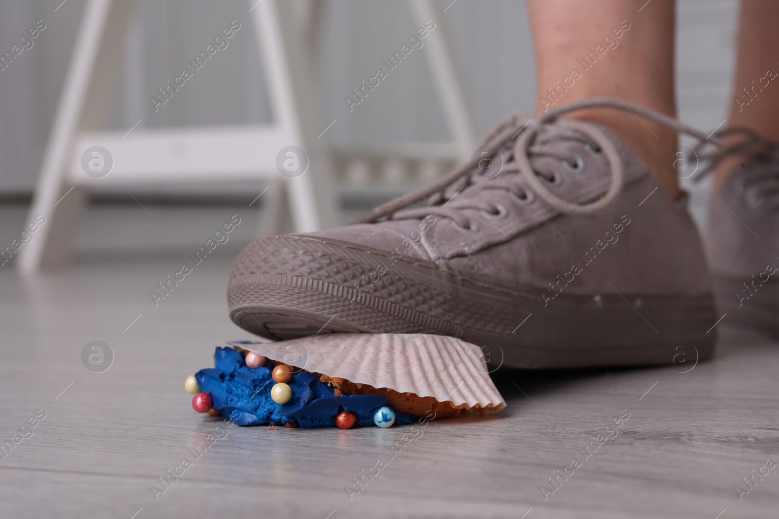 Photo of Woman stepping on dropped cupcake indoors, closeup. Troubles happen