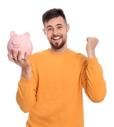 Photo of Happy young man with piggy bank on white background