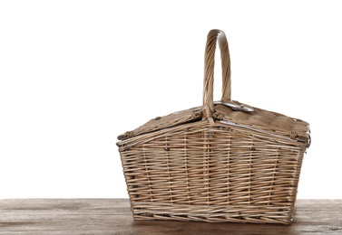 Closed wicker picnic basket on wooden table against white background