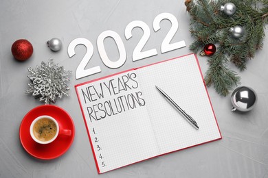 Photo of Making New Year's resolutions. Flat lay composition with notebook, 2022 numbers and festive decor on light grey background