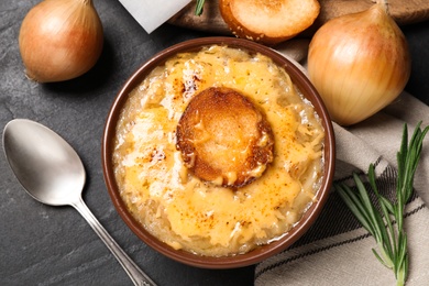Photo of Tasty homemade french onion soup served on black table, flat lay