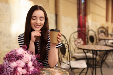 Photo of Beautiful woman with bouquet of spring flowers and coffee in outdoor cafe, space for text