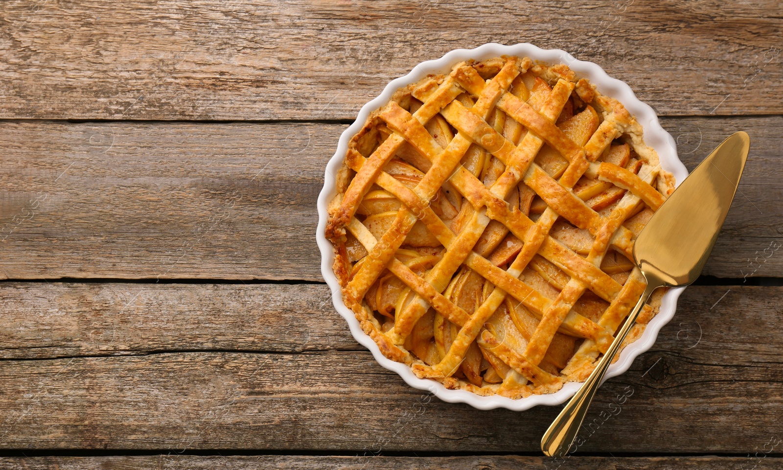 Photo of Tasty homemade quince pie and cake server on wooden table, top view. Space for text