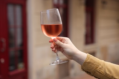 Photo of Woman holding glass of rose wine outdoors, closeup