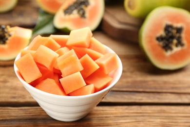 Photo of Fresh diced papaya fruit in bowl on wooden table, closeup. Space for text