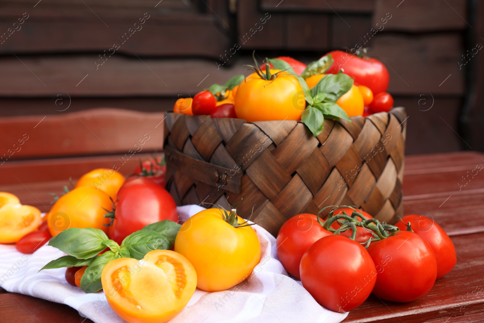 Photo of Different sorts of tomatoes with basil on wooden table