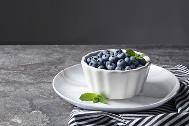 Crockery with juicy blueberries on color table