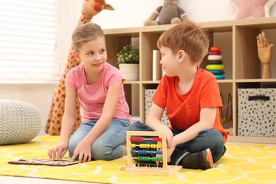 Photo of Happy children playing with math game kits on floor in room. Learning mathematics with fun