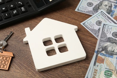 Photo of Mortgage concept. House model, key, calculator and money on wooden table